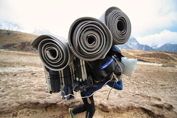 Sherpa Porter carrying a heavy load on the Everest base camp trek trails towards Gorakshep village,Nepal © InnerPeace