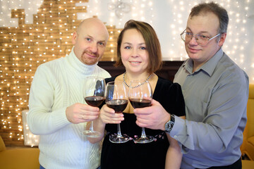 Portrait of happy woman and two men with glasses of wine