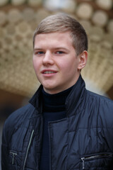 Fototapeta premium Portrait of young blond man on background of lights installation main park alley, close-up
