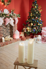 Interior of room with firtree decorated to christmas holidays, fireplace, red walls. Focus  on burning candles.