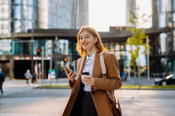 Confident businesswoman walking with her phone and coffee along city centre