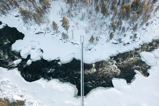 Aerial view of a bridge over a snow-covered river in Lapland