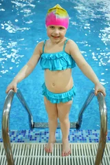 Fotobehang Little girl in a swimming hat out of the pool © Pavel Losevsky