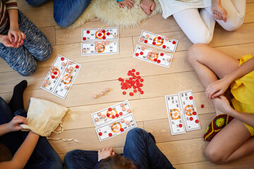 Children play russian lotto sitting on the floor, view from above
