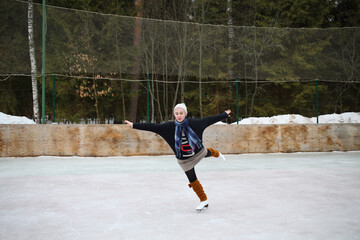 Young girl skating on one leg with arms outstretched to the sides on a skating rink