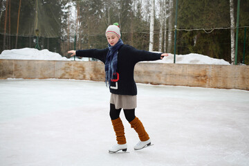 Young girl in a knitted sweater skating on a skating rink