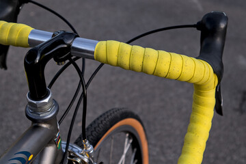 bike handlebar detail with bright yellow bar tape (bicycle cockpit, cycling) integrated shifters, brifters, black quill threaded stem, headset, titanium frame, silver aluminum bars, exposed cables