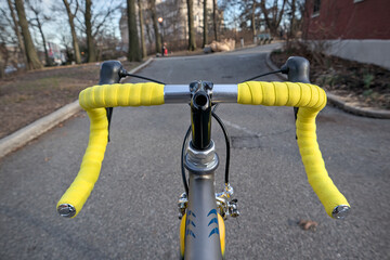 bike handlebar detail with bright yellow bar tape (bicycle cockpit, cycling) integrated shifters, brifters, black quill threaded stem, headset, titanium frame, silver aluminum bars, exposed cables