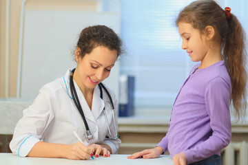 Obraz premium Health worker writing prescription for young girl in exam room, focus on woman