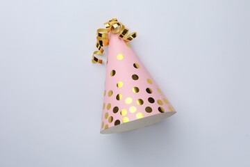 One pink party hat with serpentine streamers on light background, top view