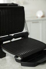 Electric grill on grey textured table in kitchen, closeup. Cooking appliance