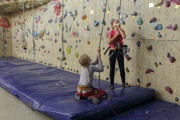 Rock climbing. Two girls in indoor climbing center, preparing to rise up.
