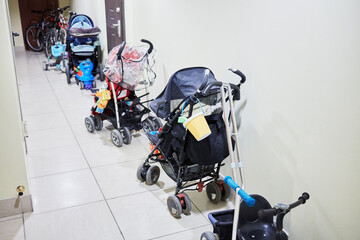 Row of baby carriages along the wall in the hallway