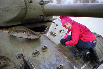 Girl in a pink jacket and hat climbed on the Soviet tank