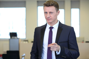 Businessman with distrustful look pointing at camera in the office - obrazy, fototapety, plakaty