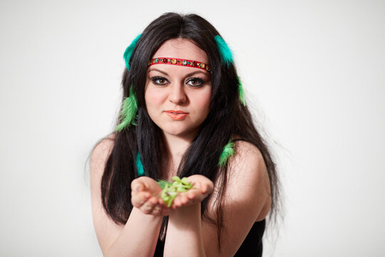 Smiling dark-haired girl model with green feathers in hair holds feathers on her hands