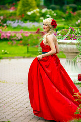 Fototapeta premium Full portrait of beautiful woman in red long dress walking in summer park