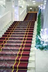 The main staircase with a carpet in the New Year decorations in the room of white marble