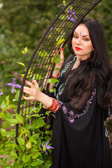 Brunette pretty woman in black sari and Indian adornment poses in garden