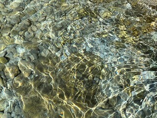 Sea clear water with stones pebbles at the bottom.