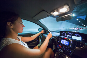 Woman drives car in illuminated tunnel