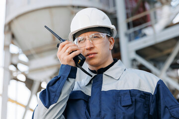 Worker talking on radio phone with colleague driving mixer truck in industry cement factory. Portrait of man working hard