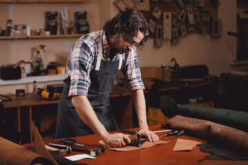 Craftsman outlining cut on leather piece in workshop