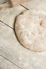 Bread with flour and rolling pin to knead on a rustic white wooden table. Top view.