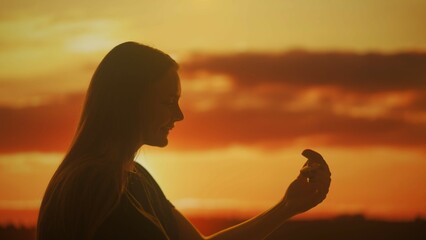 Silhouette of a woman with a box with a jewelry ring in her hands at sunset