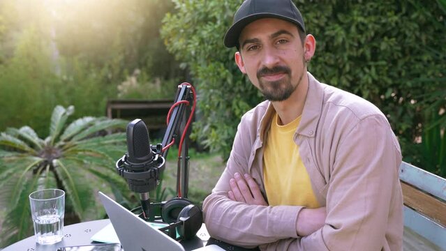 Portrait of a young man recording podcast looking at camera outdoors in spring. High quality 4k footage