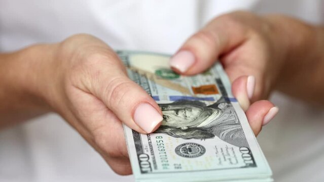 Woman pointing the stack of US Dollars towards the camera, closeup on hands