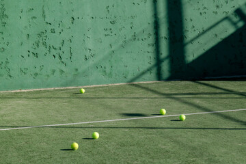 Tennis balls on green court, projected shadows.