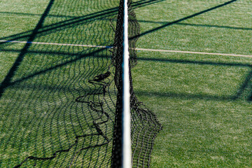 Tennis or padel net and shadows on green court.