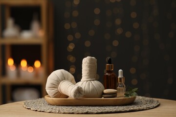 Spa composition. Herbal sacks, cosmetic products and stones on table indoors. Space for text
