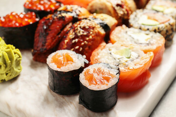 Different tasty sushi rolls on board, closeup
