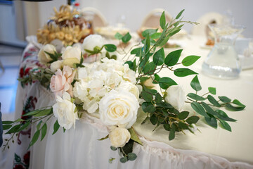 A beautiful bouquet of white flowers decorates an element of the wall of the festive hall.