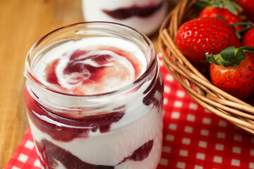 Tasty yoghurt with jam and strawberries on wooden table, closeup