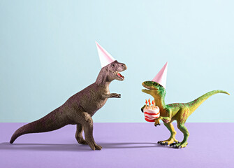 Cute happy dinosaurs in birthday hats holding cake with flaming candles on blue violet background.