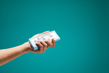 Male hand holds cash for financial income or online service isolated on green background. Arm...