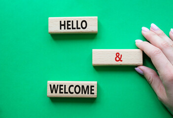Hello and Welcome symbol. Concept words Hello and Welcome on wooden blocks. Beautiful green background. Businessman hand. Business and Hello and Welcome concept. Copy space.