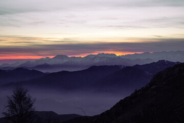 Obraz premium Staring at the horizon. Mountain range silhouette. Suggestive sunset over the alps, from Mottarone mountain (Omegna side). Piedmont - Italy.