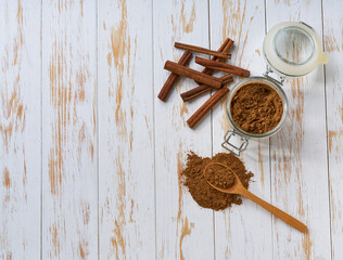 cinnamon sticks and cinnamon powder on a light wooden table, top view.