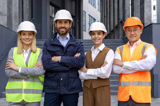 A diverse group of construction professionals with hard hats standing confidently outside a building.
