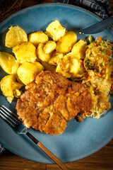 Breaded pork neck cutlet served with potatoes and salad.