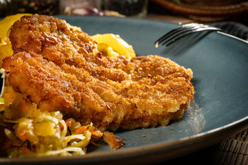 Breaded pork neck cutlet served with potatoes and salad.