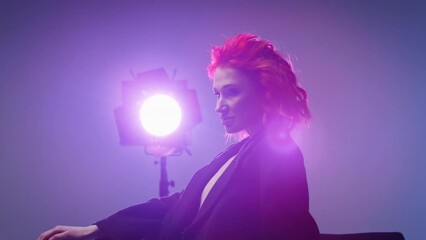 Model with red hair in front of a bright studio light. Artistic studio photography with a focus on lighting and mood. Design for workshops, lighting tutorials, and photography courses. Portrait with