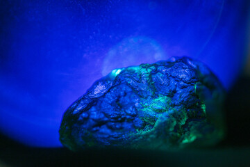 Moldavite rock close up with blue orb background