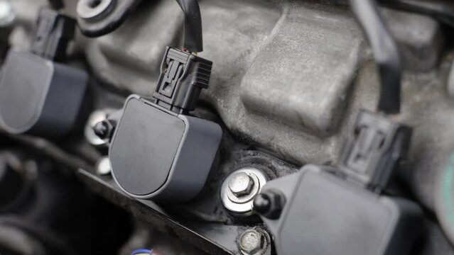 Close-Up Shot of Car Engine Bay Highlighting Engine Oil Dipstick, Electrical Connector, and Ignition Coils
