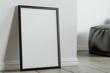 Empty thin black frame on light wooden floor with white wall behind it. Empty poster fram