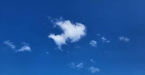 A blue sky and a white cloud that looks like a small fish